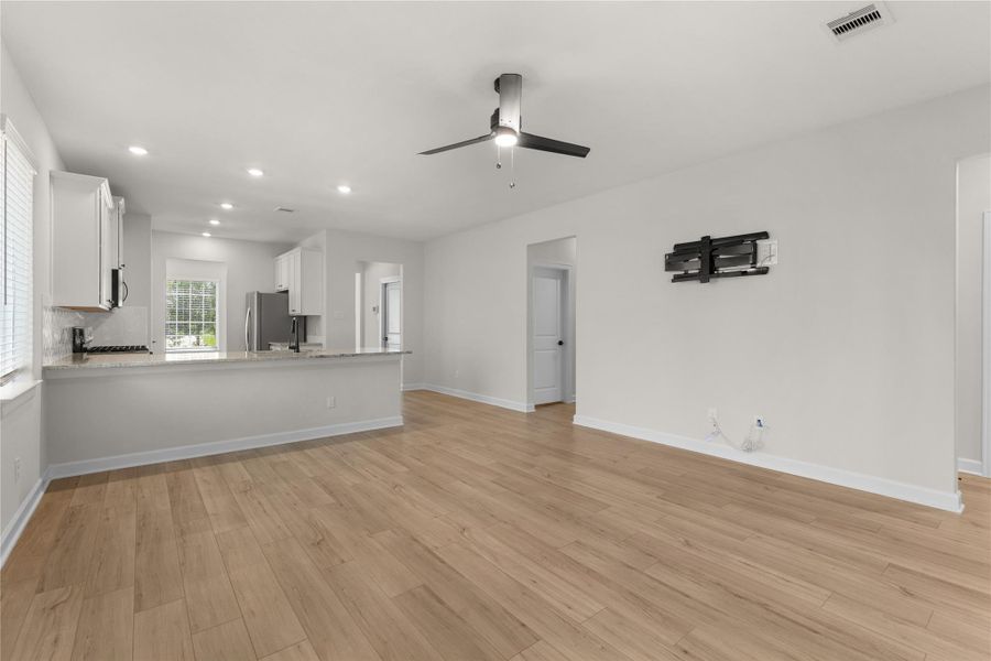 Bright and open living area with durable wood-look flooring, recessed lighting, and seamless flow into the kitchen. The open-concept layout offers plenty of space for everyday living and entertaining Bright and open living area with durable wood-look flooring, recessed lighting, and seamless flow into the kitchen. The open-concept layout offers plenty of space for everyday living and entertaining