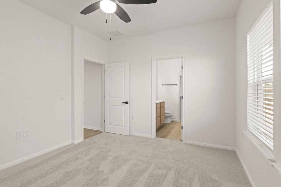 Unfurnished bedroom featuring light colored carpet, a ceiling fan, and ensuite bathroom