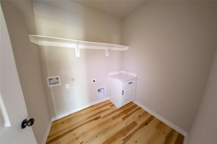 Washroom with gas dryer hookup, wood finished floors, hookup for an electric dryer, washer hookup, and cabinet space