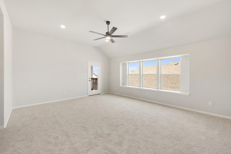 Empty room with vaulted ceiling, ceiling fan, carpet flooring, large window, and glass door