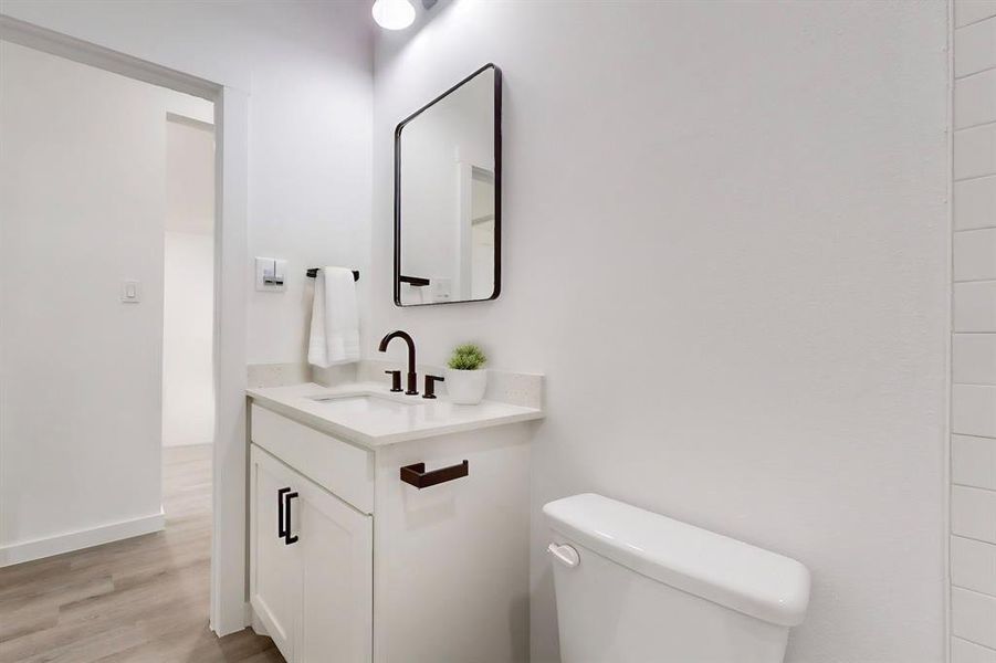 Bathroom with hardwood / wood-style floors, vanity, and toilet