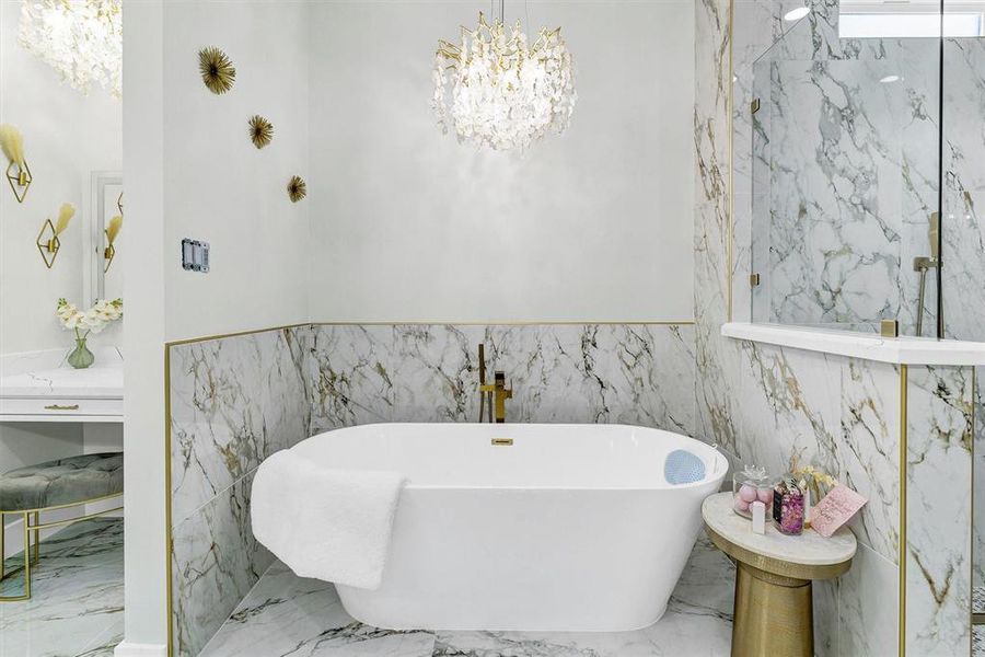 Bathroom featuring tile walls, an inviting chandelier, and a bathing tub