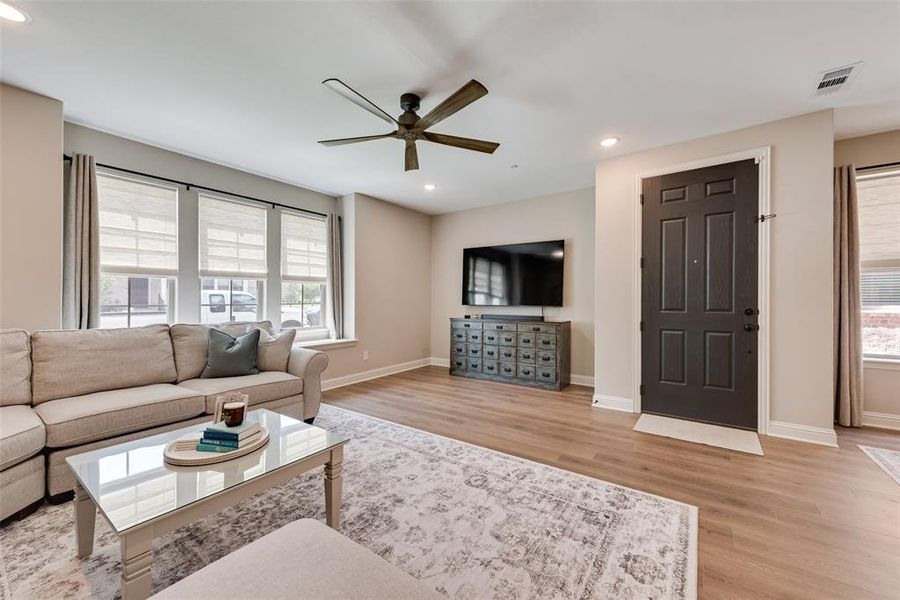Living room with plenty of natural light, light wood-type flooring, recessed lighting, and a ceiling fan