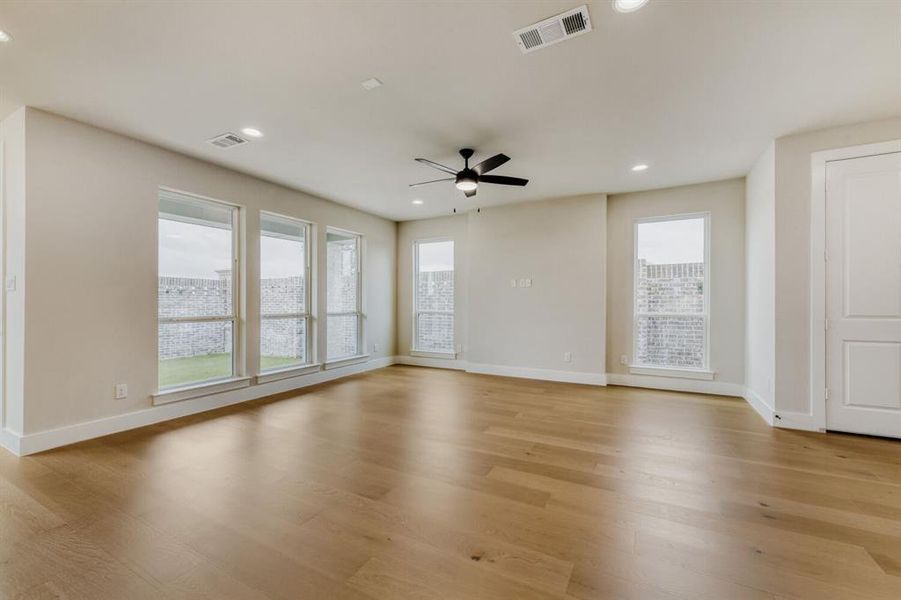 Spacious room featuring wood-finish flooring, recessed lighting, and a ceiling fan