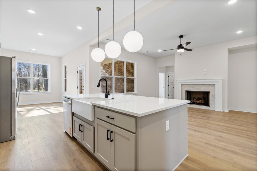 Kitchen with stainless steel appliances, a center island with sink, open floor plan, hanging light fixtures, and light wood-style flooring Kitchen with stainless steel appliances, a center island with sink, open floor plan, hanging light fixtures, and light wood-style flooring