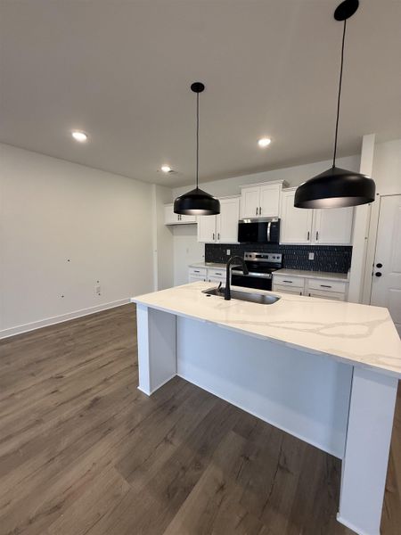 Kitchen featuring white cabinets, pendant lighting, backsplash, and dark wood-type flooring