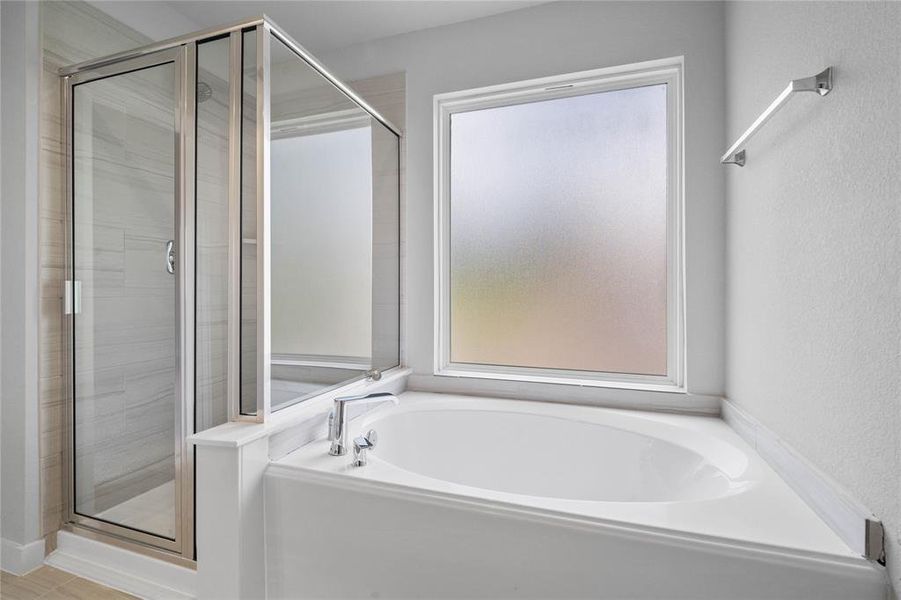 Wow! Look at this primary bathroom! Featuring dark framed walk-in shower with tile surround, separate garden tub for soaking after a long day.