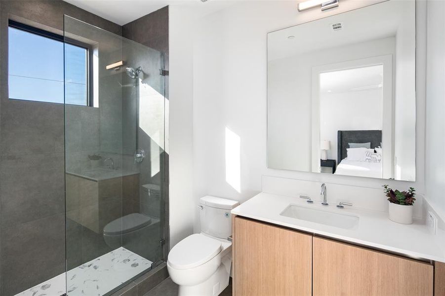 Bathroom with tiled shower, vanity, and toilet