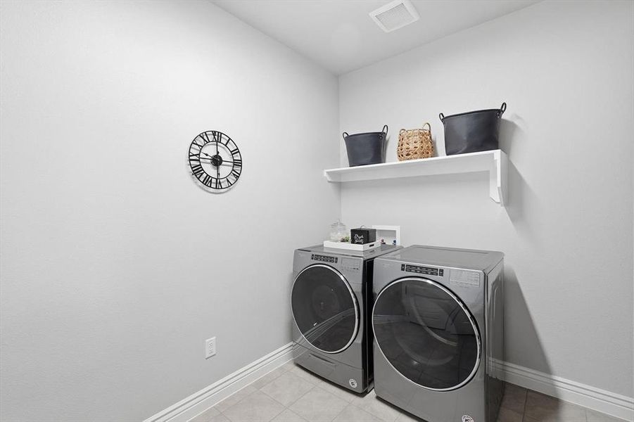 Laundry room with light tile patterned floors and washing machine and clothes dryer