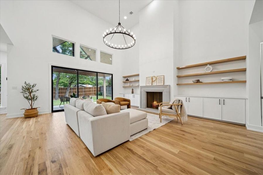 Living room featuring a high ceiling, hardwood flooring, and a notable chandelier