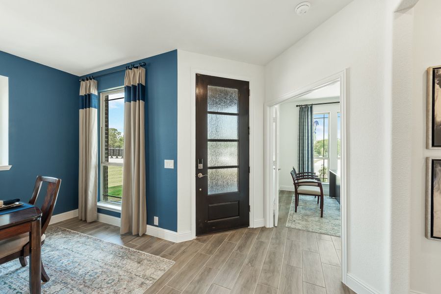 Entryway with dark front door, frosted glass panels, blue accent wall, and wood-look tile floors