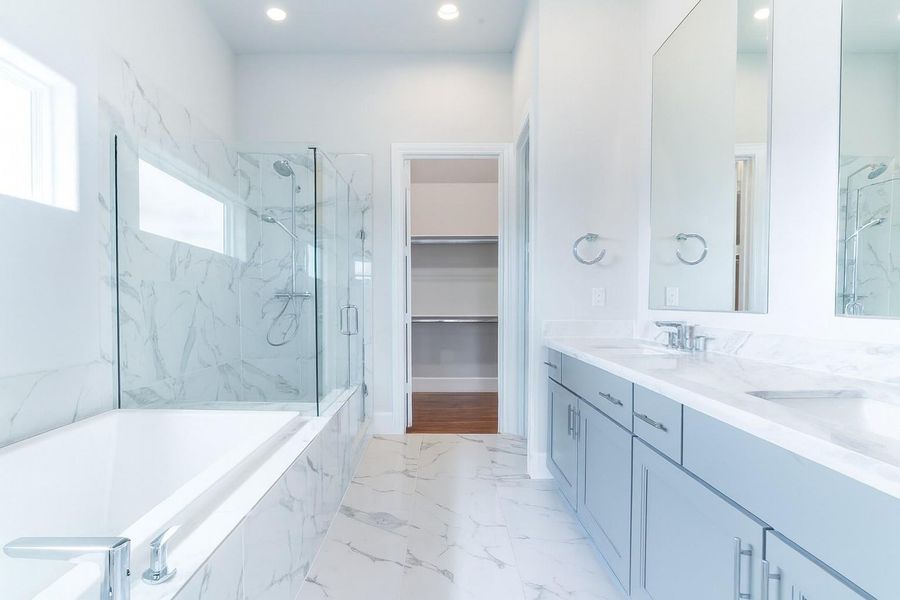 Light and bright! Primary bath with nice tub and freestanding shower leading into 1 of 3 closets. Similar plan and finishes.