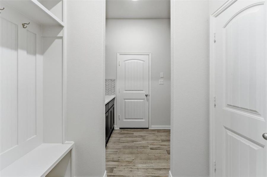 Entryway featuring built-in white cabinetry with storage, coat hooks, and bench seating