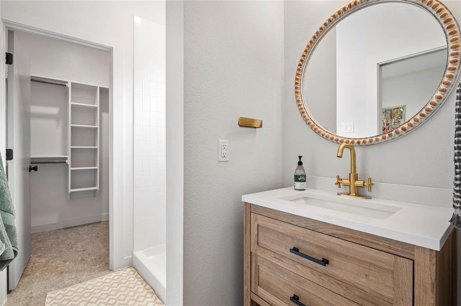 Bathroom featuring vanity, walk in shower and connected walk-in closet.