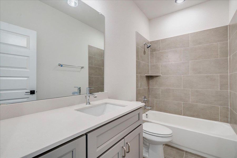 A well-appointed bath features a sleek vanity, mirror, and tiled shower/tub combination.