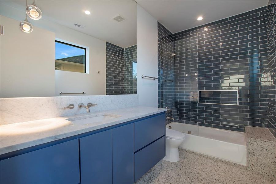 Full bathroom with tiled shower / bath combo, toilet, and vanity