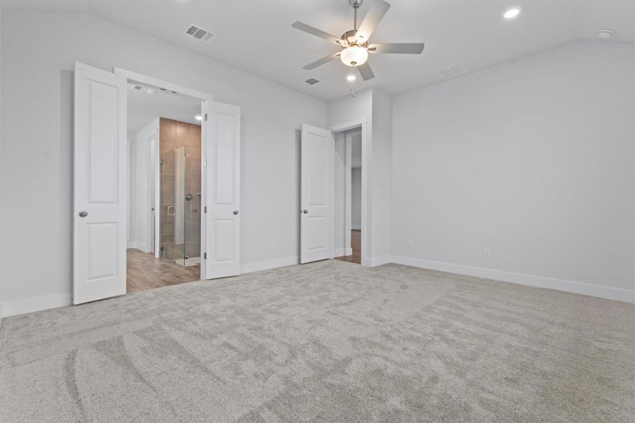 Unfurnished bedroom featuring ceiling fan, lofted ceiling, and light colored carpet