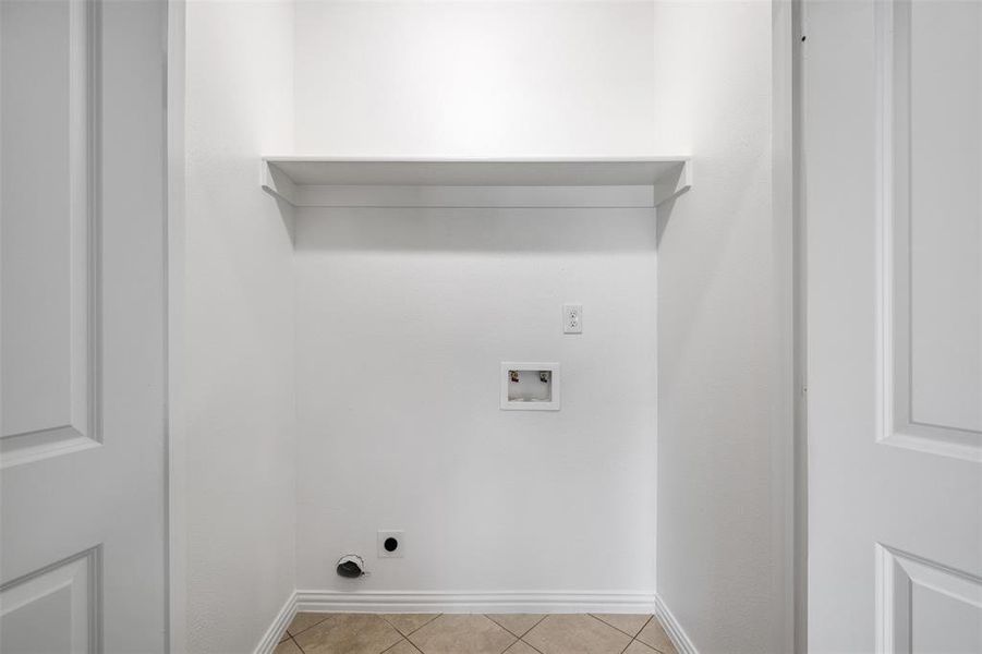 Clothes washing area featuring hookup for an electric dryer, light tile patterned floors, and hookup for a washing machine