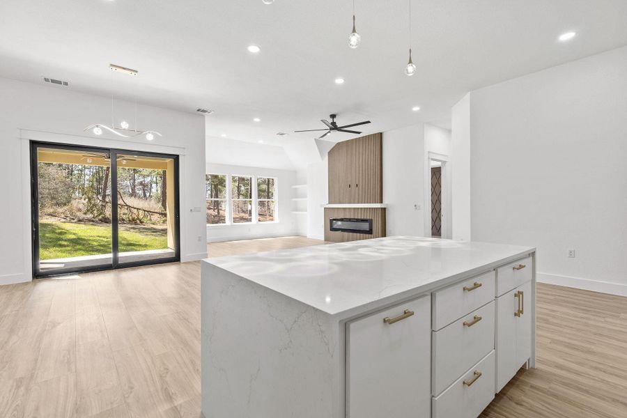 Kitchen with a kitchen island, decorative light fixtures, light wood-type flooring, and white cabinets