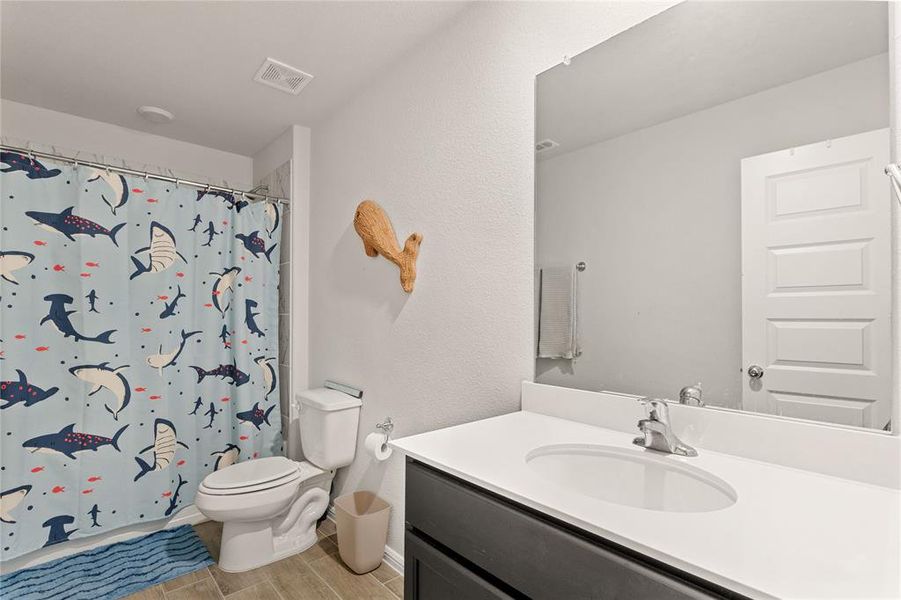 Upstairs full bathroom with vanity, wood finish floors, a shower with curtain, and a textured wall
