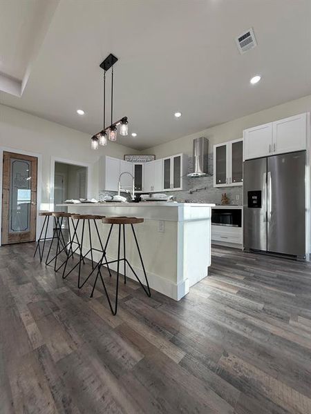 Other side view of kitchen included stainless steel fridge, separate stainless steel microwave, and 36" inch stainless steel stove.  Designer lightning inland light.