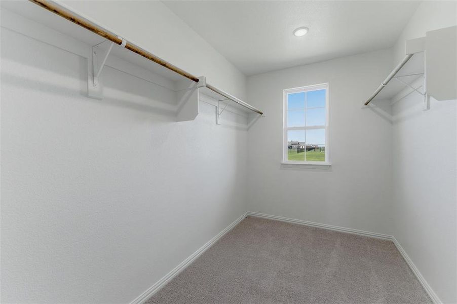 Expansive walk-in closet featuring light gray carpeting, crisp white walls, and a recessed ceiling light Expansive walk-in closet featuring light gray carpeting, crisp white walls, and a recessed ceiling light