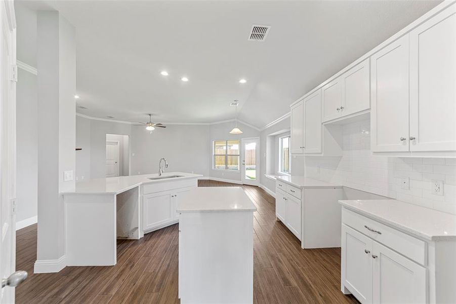 Kitchen with white cabinets, vaulted ceiling, ceiling fan, and dark wood-type flooring