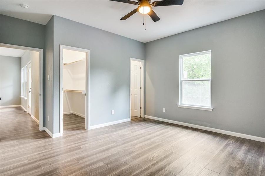 Unfurnished bedroom featuring ceiling fan, wood-type flooring, a closet, and a spacious closet