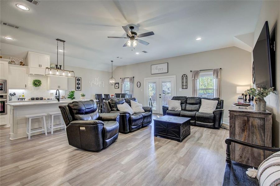 Living room with french doors, vaulted ceiling, ceiling fan, sink, and light hardwood / wood-style flooring