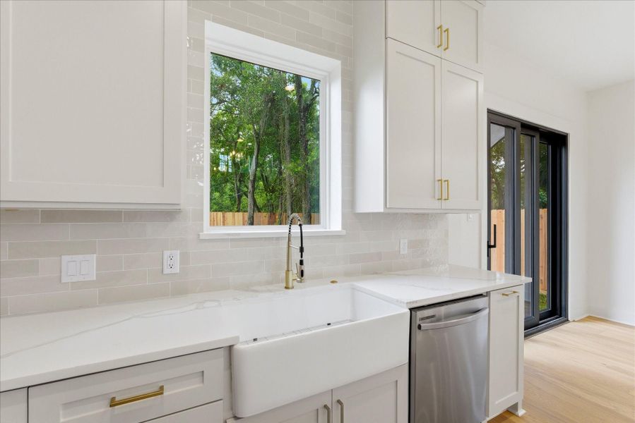 A lovely apron-front sink is perfectly positioned beneath a picture window, bringing in natural light and making everyday moments, even washing dishes, feel nice and homey.