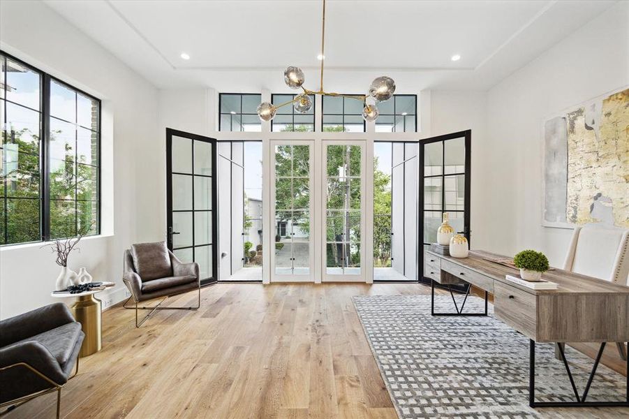 This east-facing Guest Suite No. 1 or study, adorned with 7" European Engineered White Oak Flooring, is drenched in sunlight, courtesy of a wall of windows and an adjacent private balcony boasting treetop views. Recessed lighting and Visual Comfort chandelier lighting further enhance the ambiance, creating a serene and inviting space for work or relaxation.