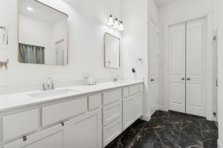 Full bathroom with a stall shower, dark marble finish floors, double vanity, and a closet Full bathroom with a stall shower, dark marble finish floors, double vanity, and a closet