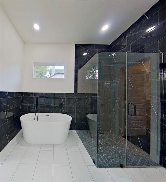 Bathroom featuring tile walls, a freestanding bath, wainscoting, a stall shower, and tile patterned flooring