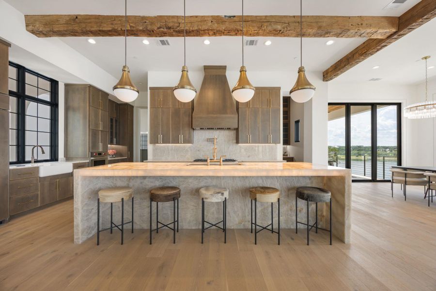 Chef's kitchen with illuminated island seating, rich wooden beams, and views to the waterfront. Chef's kitchen with illuminated island seating, rich wooden beams, and views to the waterfront.