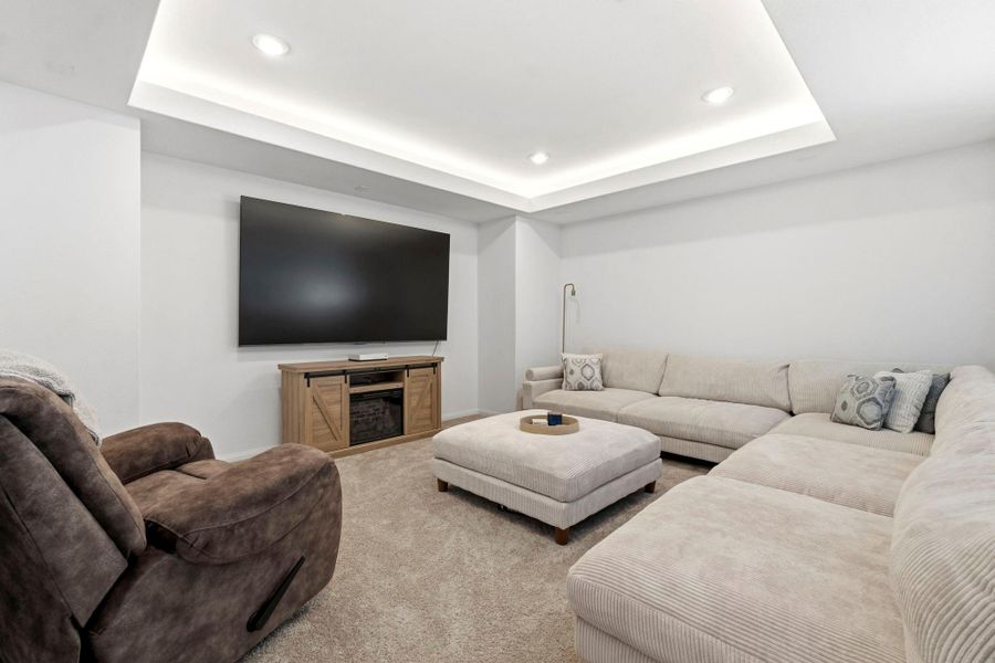 This cozy living room features plush carpet and is brightened by recessed lighting and offers a perfect setting for relaxation and entertainment.