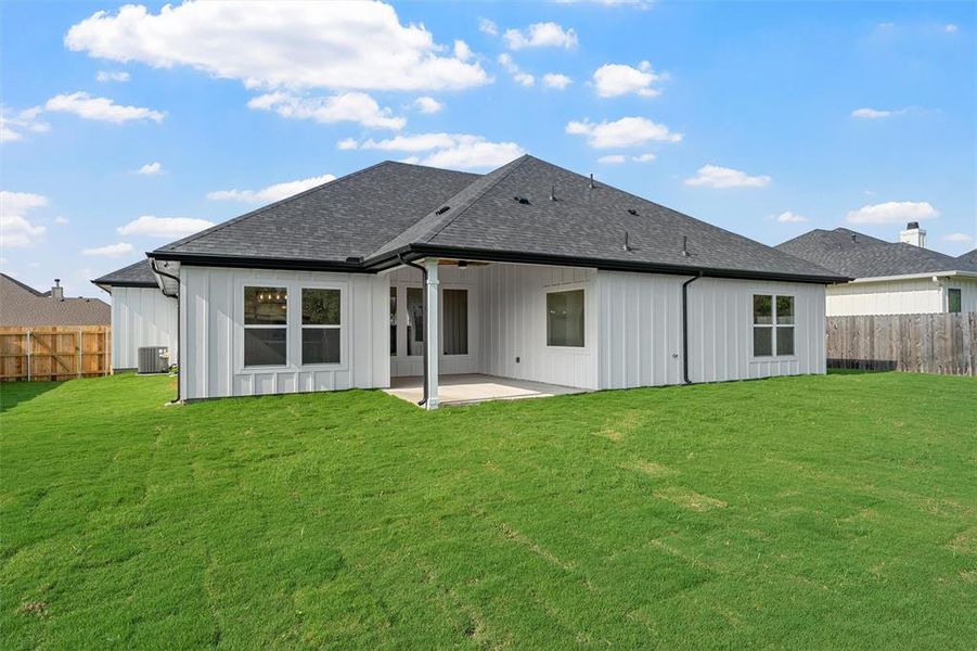 Rear view of house featuring a fenced backyard, a patio area, roof with shingles, and board and batten siding Rear view of house featuring a fenced backyard, a patio area, roof with shingles, and board and batten siding