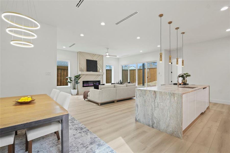 Dining space with a fireplace, light wood finished floors, recessed lighting, and ceiling fan Dining space with a fireplace, light wood finished floors, recessed lighting, and ceiling fan