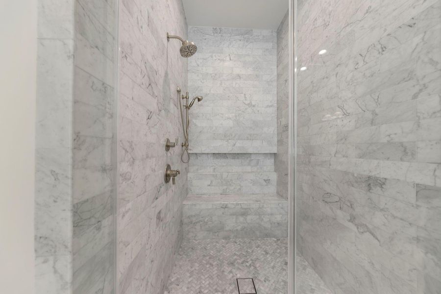 Luxurious marble walk-in shower featuring floor-to-ceiling tile, a built-in bench, and elegant fixtures for a true spa-like experience.