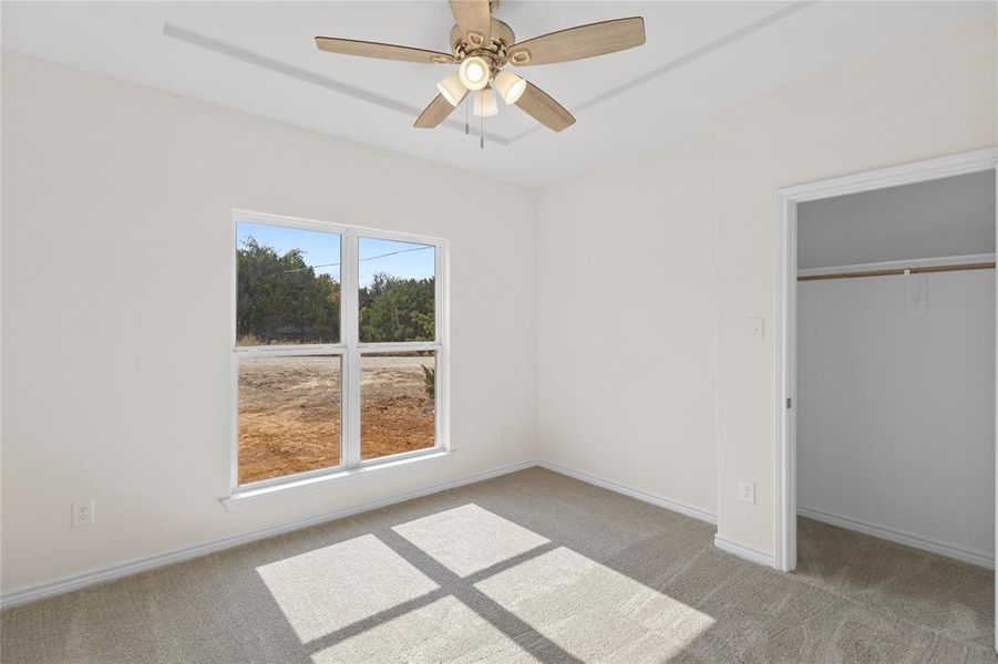 Unfurnished bedroom with light colored carpet, a closet, and a ceiling fan Unfurnished bedroom with light colored carpet, a closet, and a ceiling fan