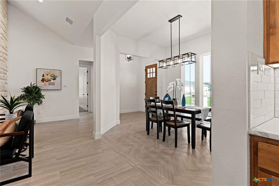 Dining room featuring lofted ceiling, light wood-type flooring, and a chandelier