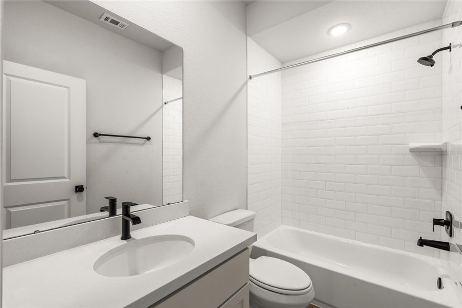 Secondary bathroom featuring a modern vanity with a black faucet and a pristine white subway tile shower with matching black fixtures.
