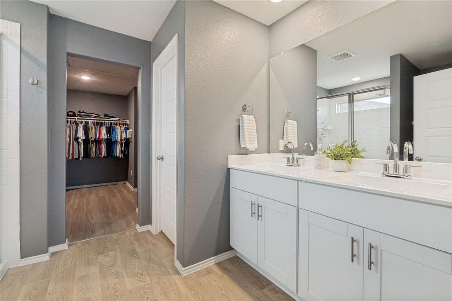 Double vanity in this primary bath features ample counter space and a convenient walk-in closet beyond.