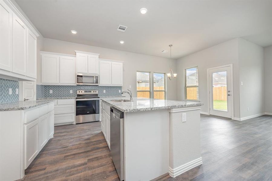 Kitchen featuring white cabinets, hanging light fixtures, dark hardwood / wood-style floors, an island with sink, and appliances with stainless steel finishes