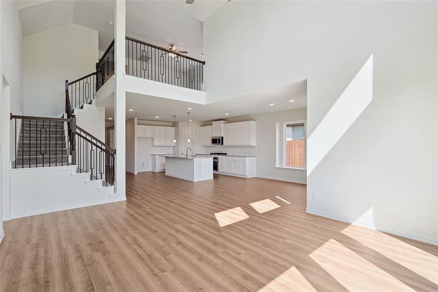 Unfurnished living room with light hardwood / wood-style floors, high vaulted ceiling, sink, and ceiling fan