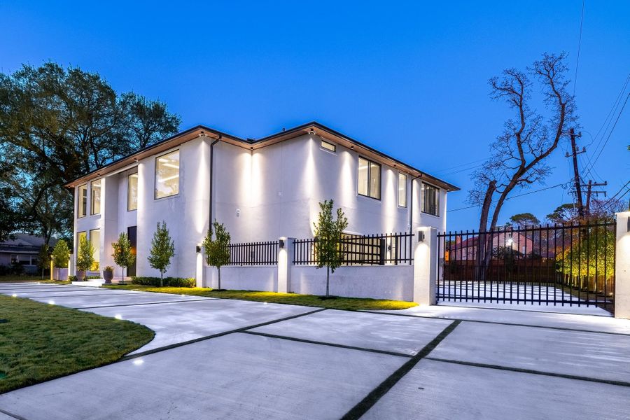 Front elevation at dusk highlighting the private drive and gated entry approach. Front elevation at dusk highlighting the private drive and gated entry approach.