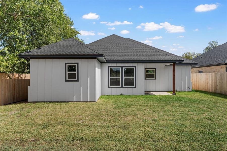 Back of property featuring a fenced backyard, roof with shingles, and a patio area