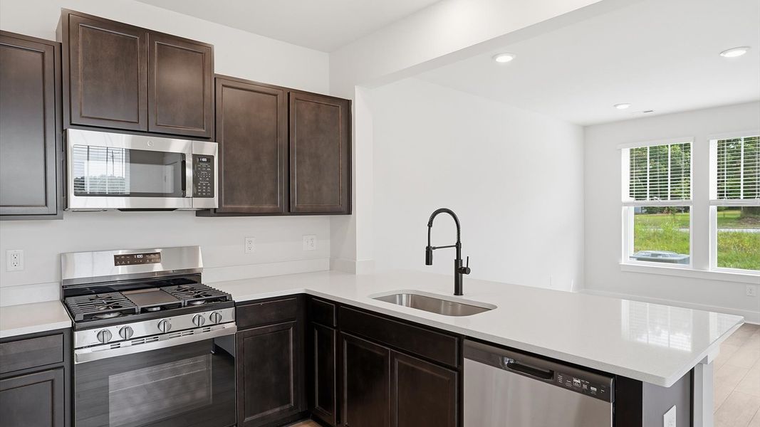 Open-concept kitchen designed to maximize both efficiency and entertaining potential by DRB Homes