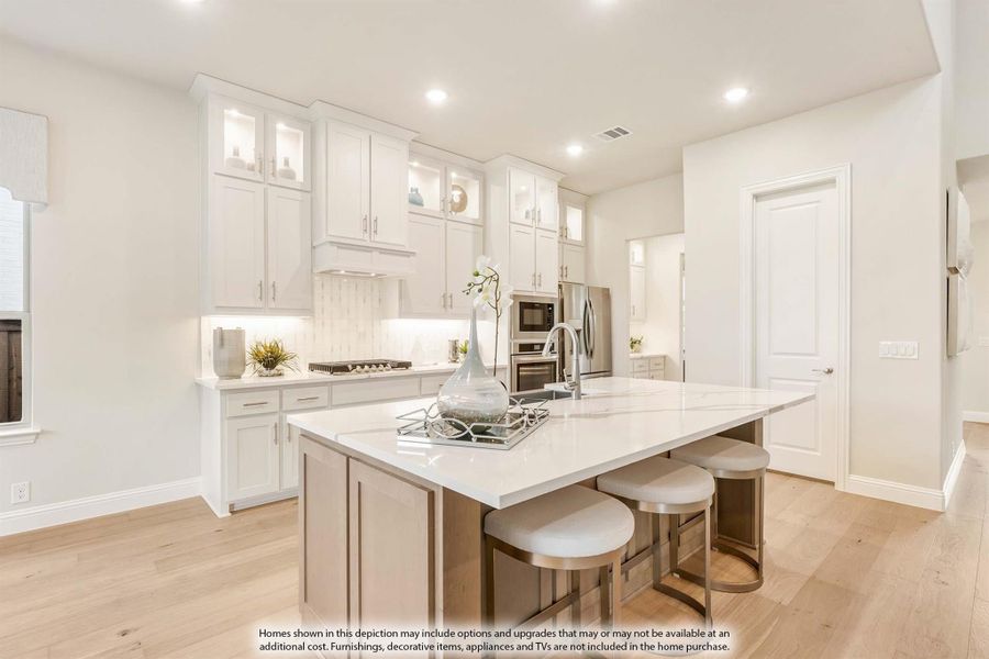Kitchen with white cabinets, large island with seating, quartz countertops, and light hardwood floors