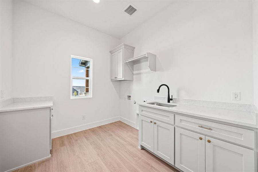Laundry room featuring cabinet space, hookup for a washing machine, light wood finished floors, and recessed lighting Laundry room featuring cabinet space, hookup for a washing machine, light wood finished floors, and recessed lighting