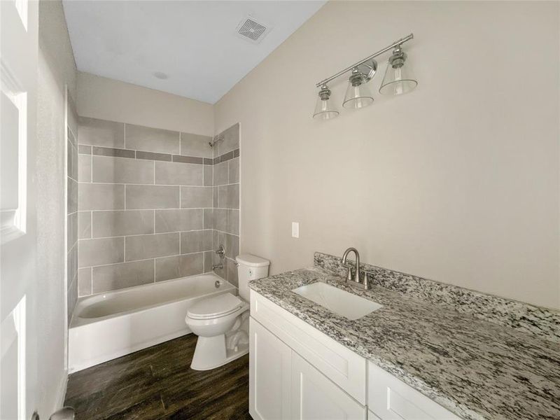 Full bath with  shower combination, dark wood-style floors, and vanity